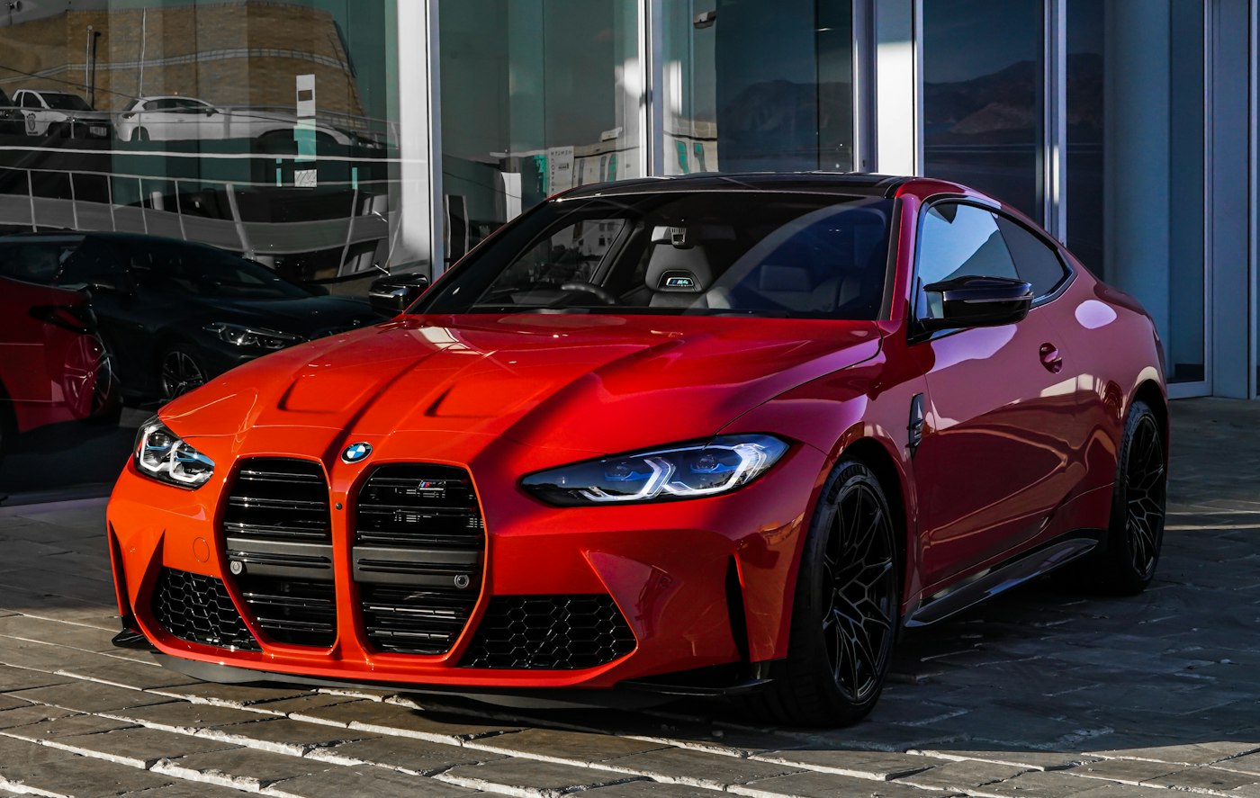 Red coupe parked outside a glass building